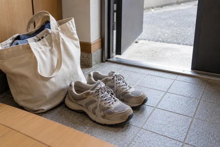 日常の玄関に置かれた運動靴と買い物袋